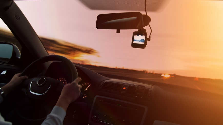 Žena drží volant a ide po ceste. Za spätným zrkadlom je umiestnená autokamera.