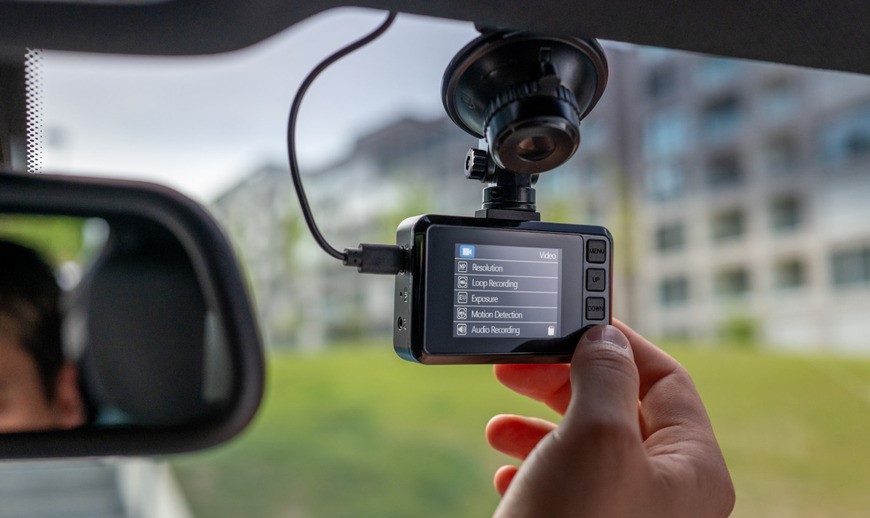 Autokamera s displejom na čelnom skle, uchytená pomocou prísavky.