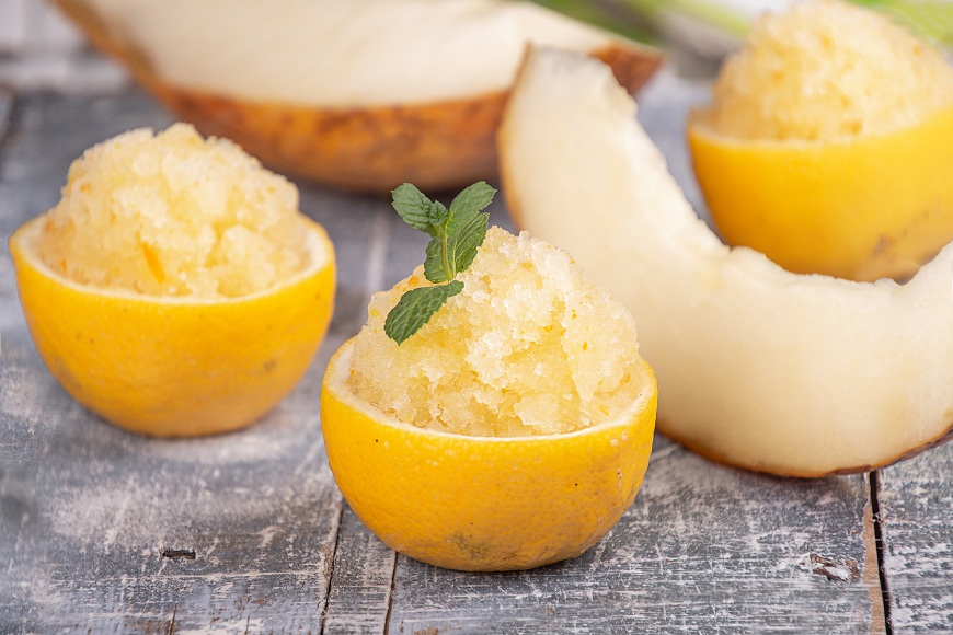 Ako pripraviť domácu zmrzlinu so zmrzlinovačom aj bez neho Citrónový sorbet servírovaný v citrónovej šupke. V pozadí je žltý melón.