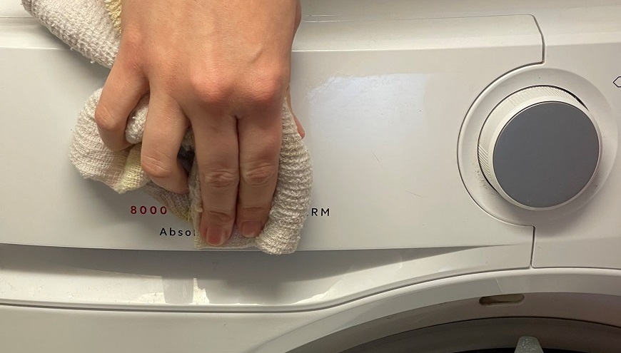 Žena utiera sušičku AEG handričkou.