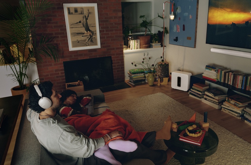 Je až neuveriteľné, aký zvuk si môžete užiť doma. Sonos uvádza nový soundbar a slúchadlá muž v obývacej izbe so slúchadlami Sonos sleduje tv so soundbarom Sonos