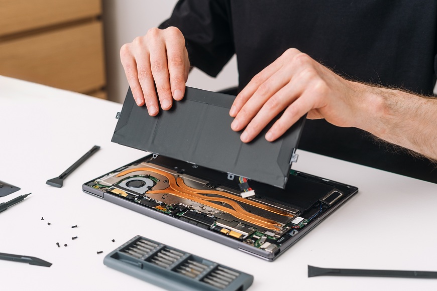 Ako vymeniť batériu v notebooku? Muž dáva novú batériu do notebooku.