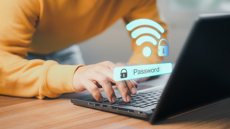 Ako pripojiť notebook k internetu? Muž zadáva heslo k Wi-Fi do notebooku. Nad notebookom je symbol pre Wi-Fi a heslo.
