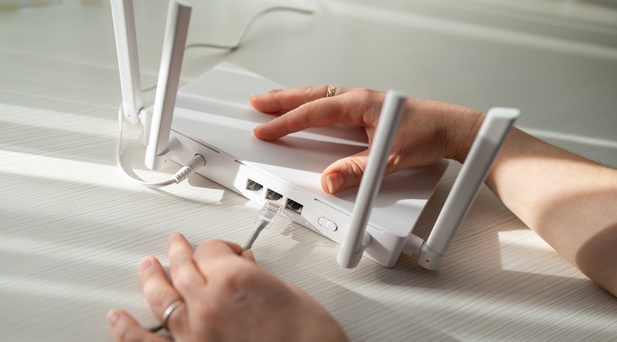 Ako pripojiť notebook k internetu? Žena zapája ethernetový kábel k routeru