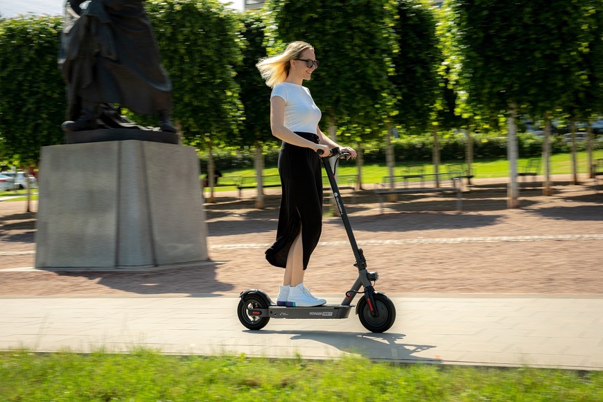 žena jazdí na elektrokolobežke v parku