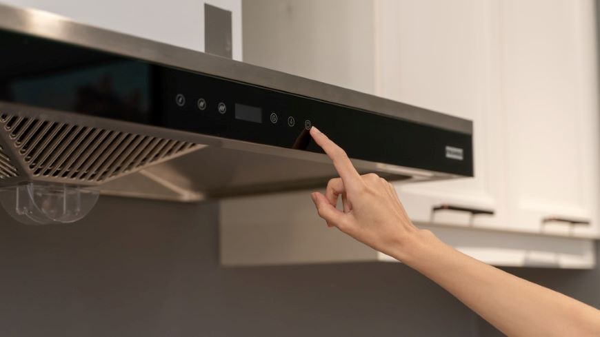 Ako vybrať digestor? Zvoľte správne typ a výkon detail ruky, ktorá zapína digestor