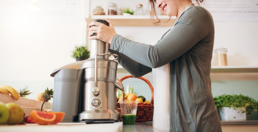 žena v kuchyni pripravuje fresh z ovocia v odšťavovači