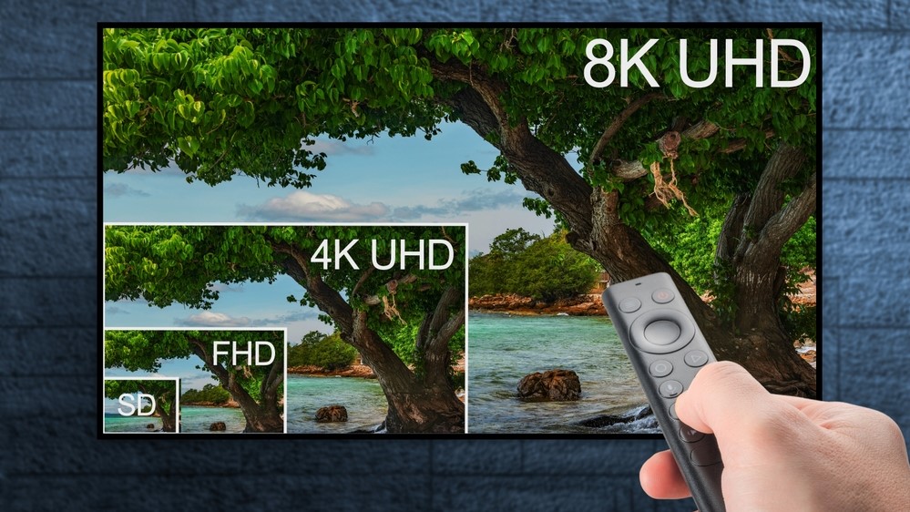 Ruka ovláda diaľkový ovládač smerom k televízoru.