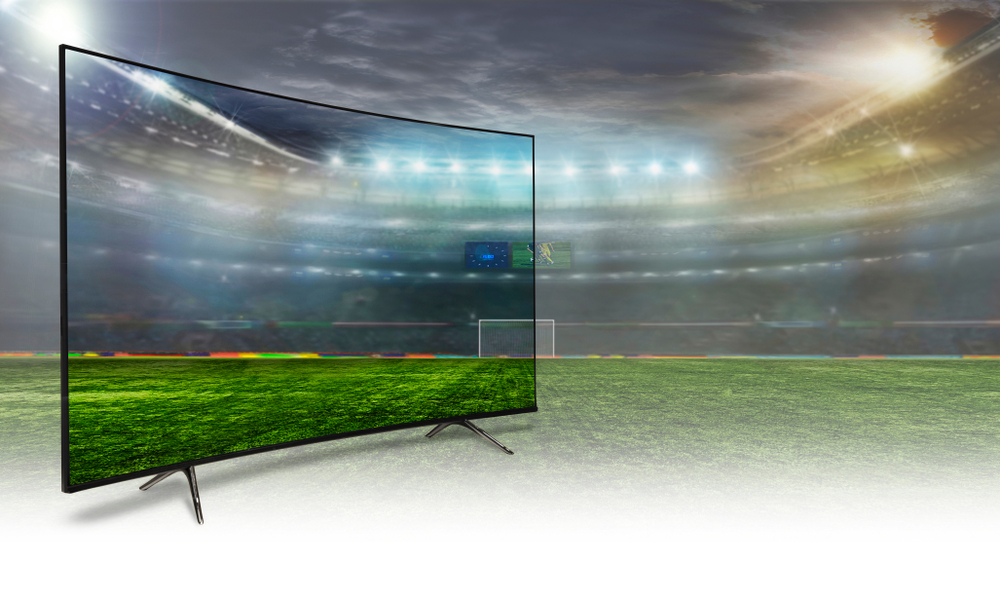 Oblý televízor položený na futbalovom trávniku na štadióne.