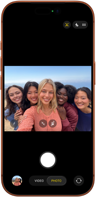 iPhone 17 Pro v kozmickej oranžovej farbe, pohľad spredu, na obrazovke je predná kamera Center Stage so skupinovým selfie piatich ľudí vycentrovaných v zábere